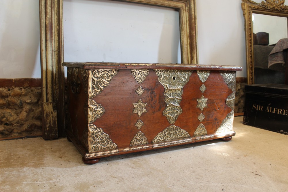 An antique warm brown teak wooden chest adorned with elaborate pierced brass plates, star-shaped metal appliques, and brass stud detailing. View XII