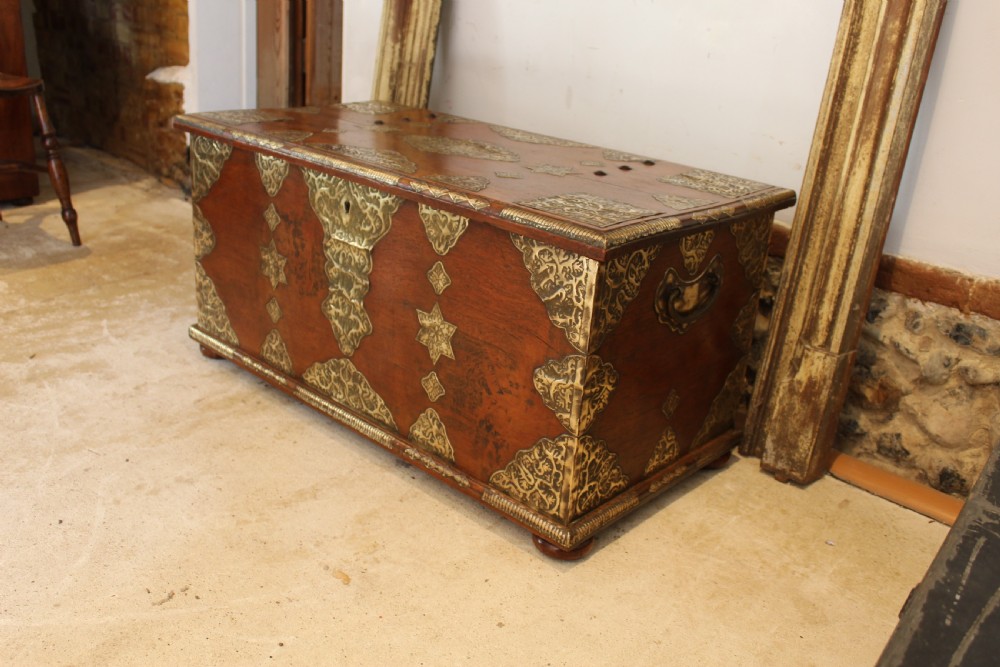 An antique warm brown teak wooden chest adorned with elaborate pierced brass plates, star-shaped metal appliques, and brass stud detailing. View XIII