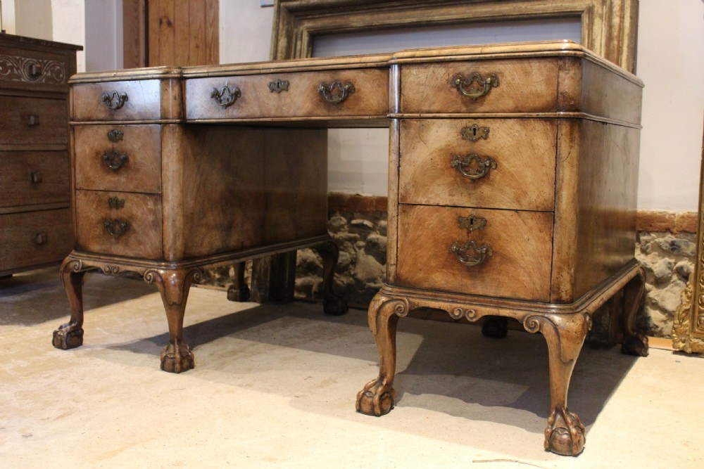 An early twentieth-century Queen Anne style burr walnut pedestal desk featuring carved cabriole legs with claw and ball feet, brass handles, and a leather writing surface. View VIII