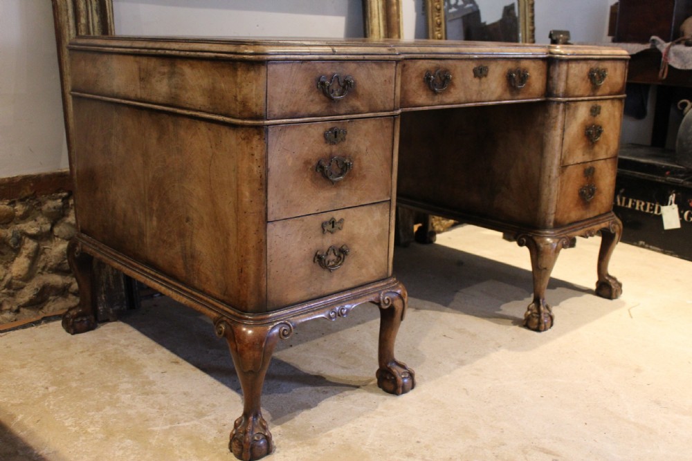 An early twentieth-century Queen Anne style burr walnut pedestal desk featuring carved cabriole legs with claw and ball feet, brass handles, and a leather writing surface. View XIII