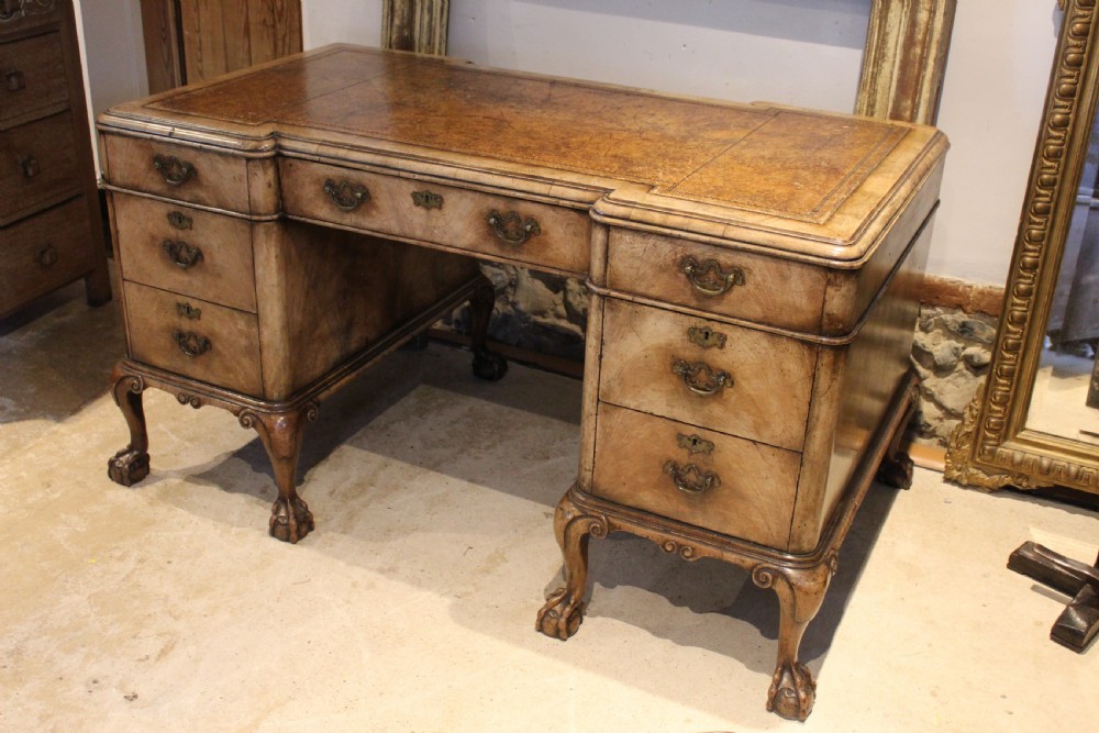 An early twentieth-century Queen Anne style burr walnut pedestal desk featuring carved cabriole legs with claw and ball feet, brass handles, and a leather writing surface. View XIV