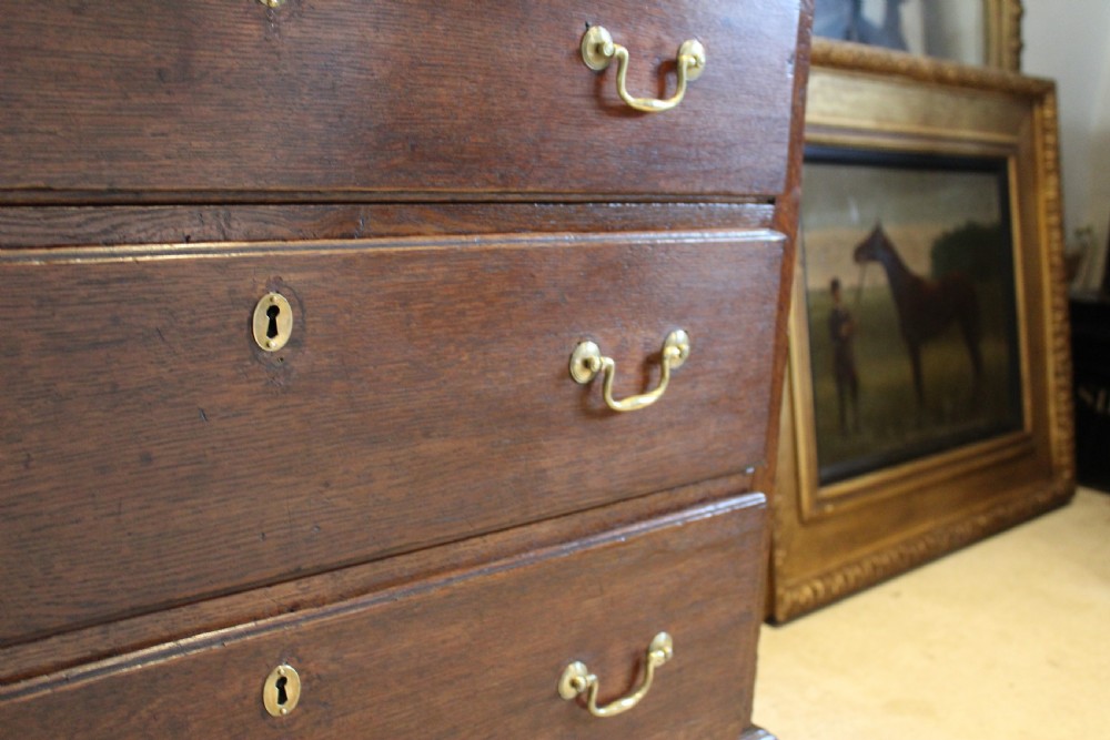 An 18th-century Georgian oak chest of drawers featuring brass swan-neck handles, a central carved arch door, and bracket feet. View VIII