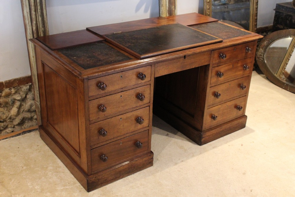 A Victorian mahogany pedestal desk fitted with a central hinged writing slope, leather top inserts, and graduated drawers with turned wooden handles.