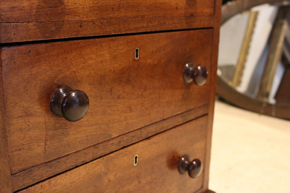A Victorian mahogany pedestal desk fitted with a central hinged writing slope, leather top inserts, and graduated drawers with turned wooden handles. View II