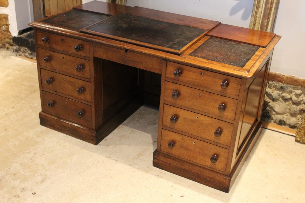 A Victorian mahogany pedestal desk fitted with a central hinged writing slope, leather top inserts, and graduated drawers with turned wooden handles. View III
