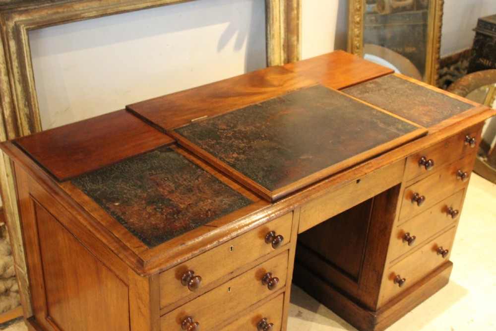 A Victorian mahogany pedestal desk fitted with a central hinged writing slope, leather top inserts, and graduated drawers with turned wooden handles. View IV