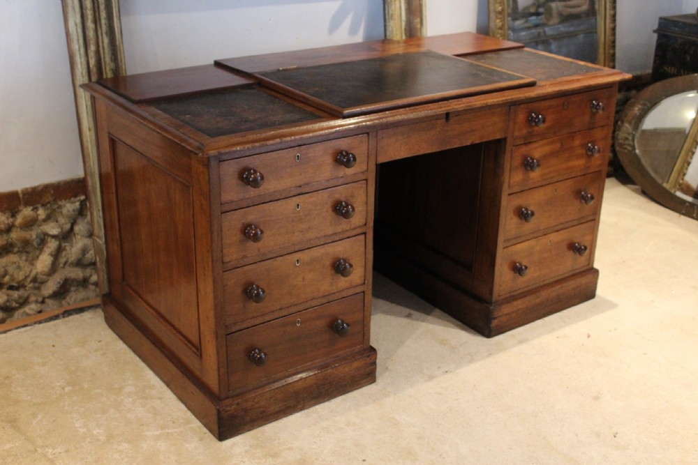 A Victorian mahogany pedestal desk fitted with a central hinged writing slope, leather top inserts, and graduated drawers with turned wooden handles. View V