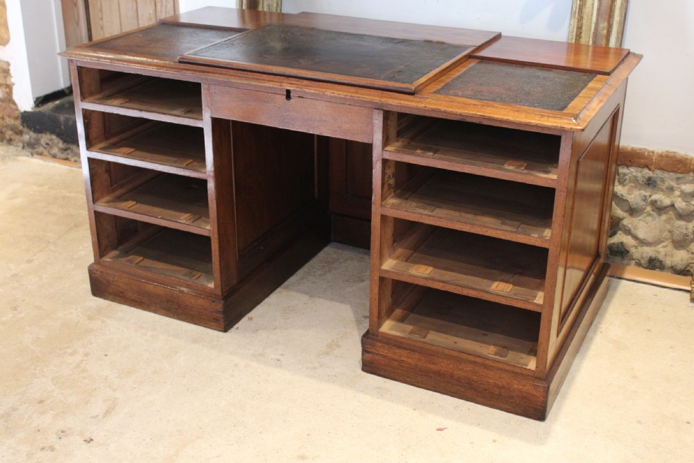 A Victorian mahogany pedestal desk fitted with a central hinged writing slope, leather top inserts, and graduated drawers with turned wooden handles. View VI