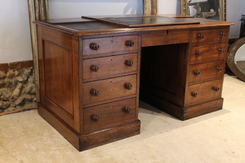 A Victorian mahogany pedestal desk fitted with a central hinged writing slope, leather top inserts, and graduated drawers with turned wooden handles. View X