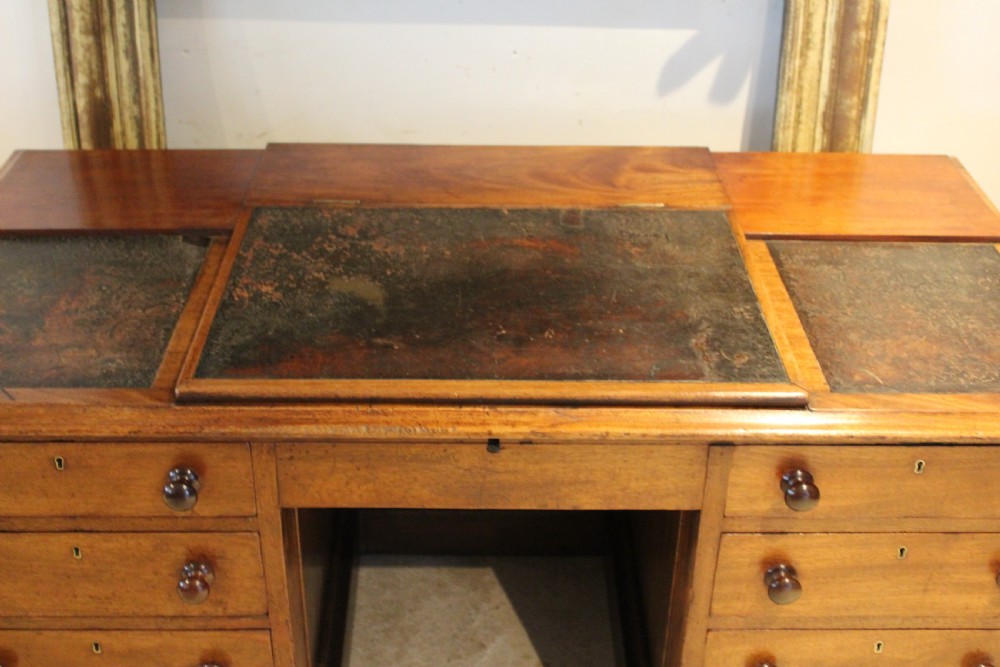A Victorian mahogany pedestal desk fitted with a central hinged writing slope, leather top inserts, and graduated drawers with turned wooden handles. View XII