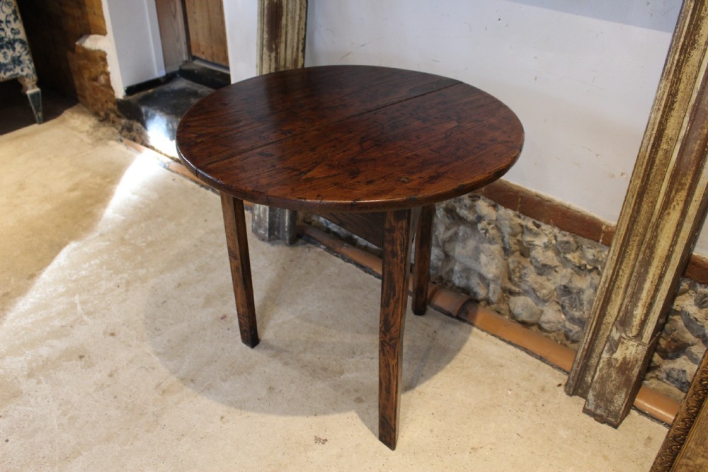 A George III circular elm cricket table featuring a dark planked timber top supported by three splayed wooden legs. View VI