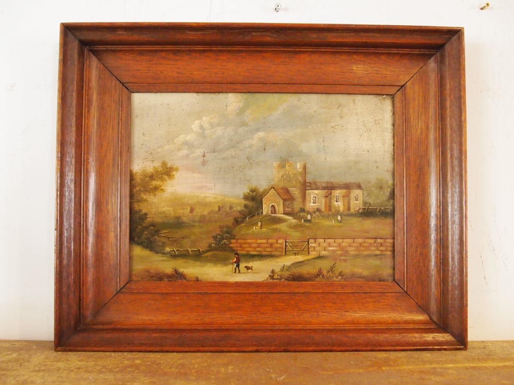 A 19th-century naive oil painting on board depicting a rural church scene with a figure walking a dog, set within a wide wooden frame.