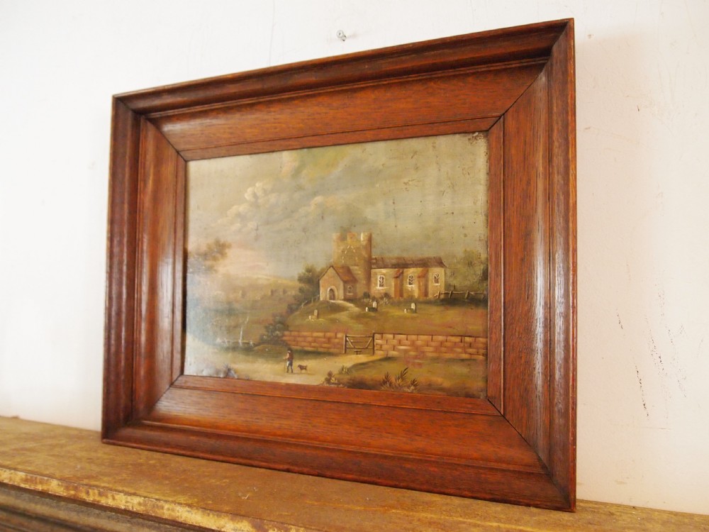 A 19th-century naive oil painting on board depicting a rural church scene with a figure walking a dog, set within a wide wooden frame. View V