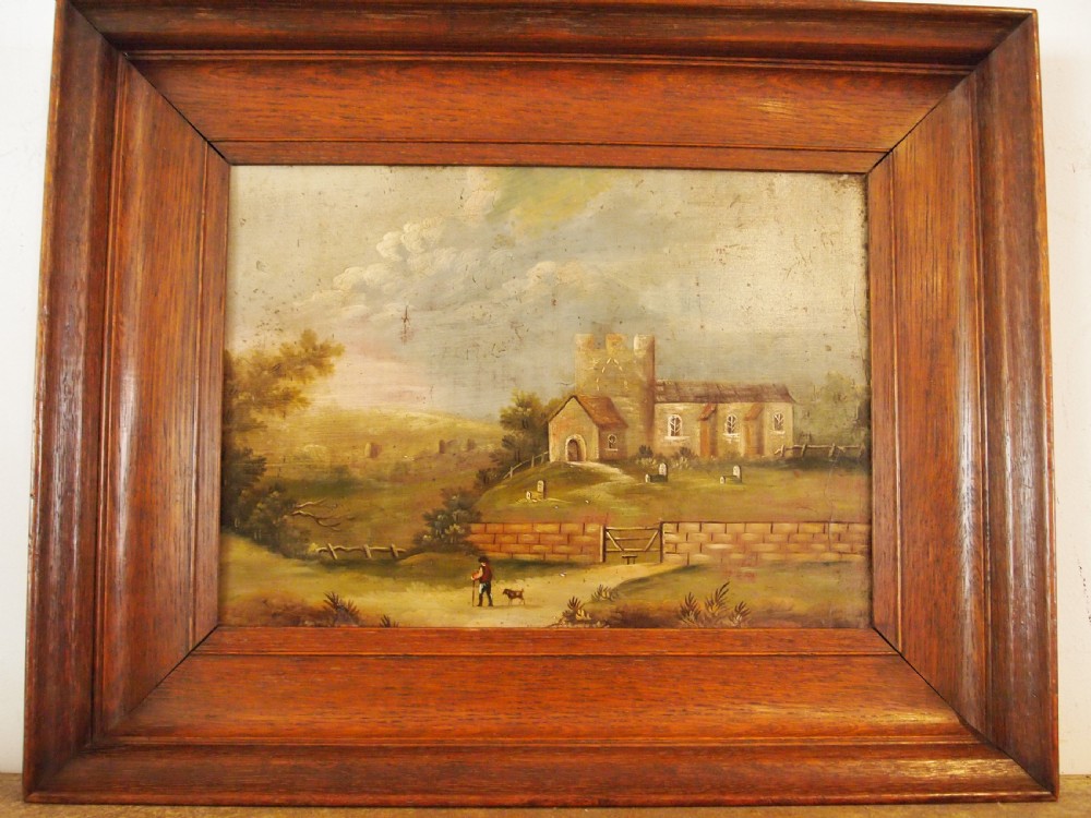 A 19th-century naive oil painting on board depicting a rural church scene with a figure walking a dog, set within a wide wooden frame. View XII
