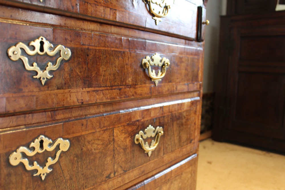 A George II walnut bureau featuring a slanted fall-front flap over four graduated drawers with brass handles, resting on bracket feet. View III