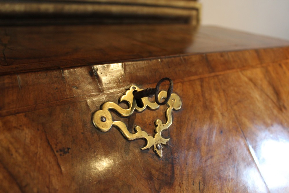A George II walnut bureau featuring a slanted fall-front flap over four graduated drawers with brass handles, resting on bracket feet. View X