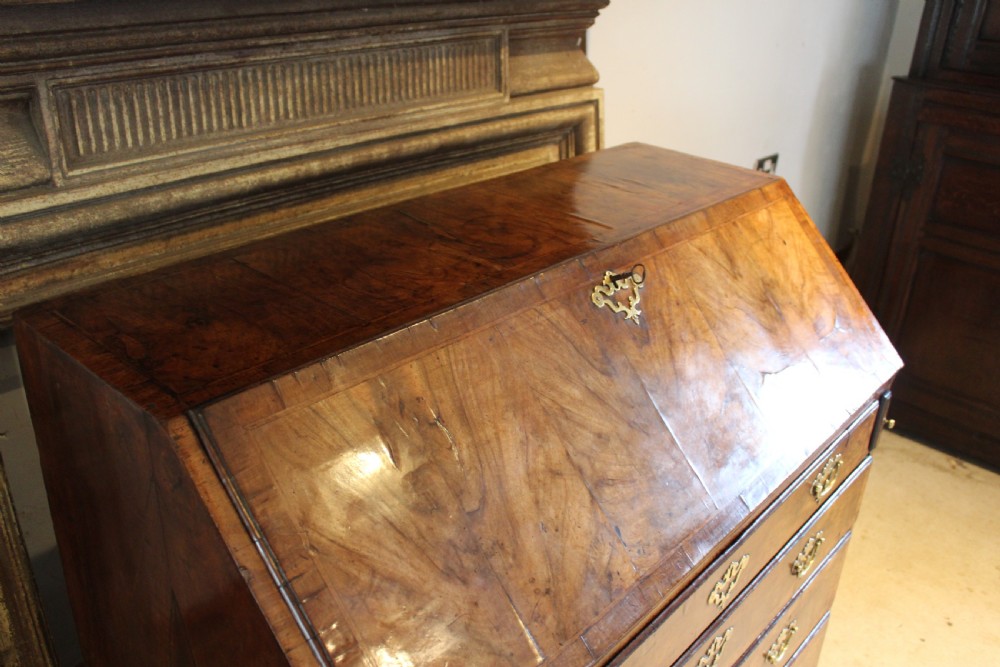A George II walnut bureau featuring a slanted fall-front flap over four graduated drawers with brass handles, resting on bracket feet. View XI