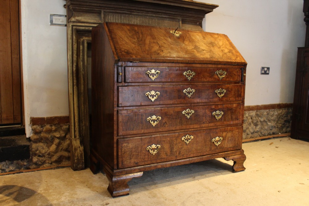 A George II walnut bureau featuring a slanted fall-front flap over four graduated drawers with brass handles, resting on bracket feet. View XIII