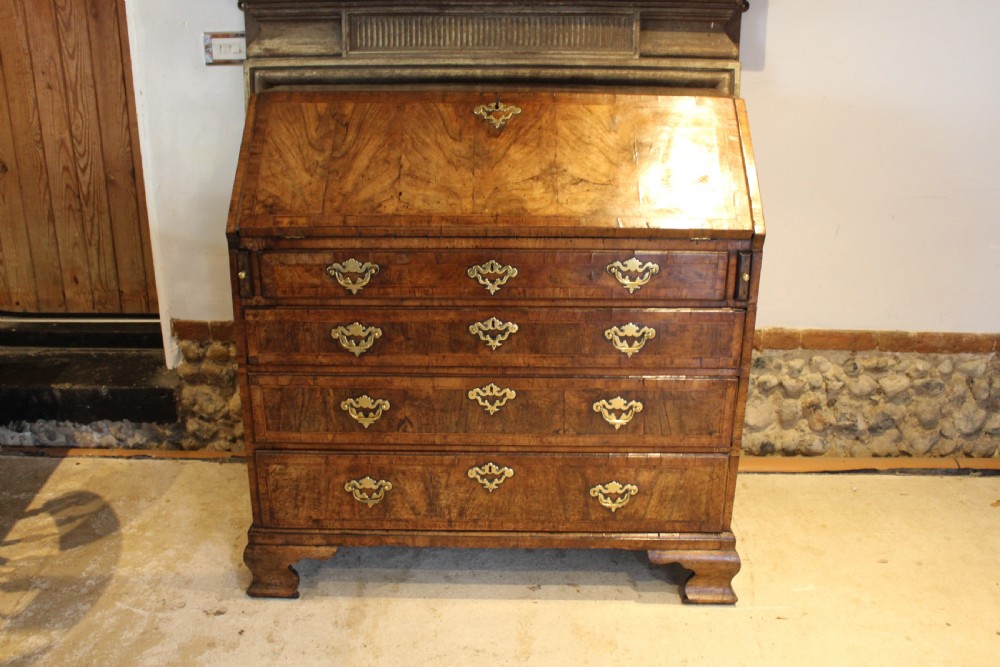 A George II walnut bureau featuring a slanted fall-front flap over four graduated drawers with brass handles, resting on bracket feet. View XIX