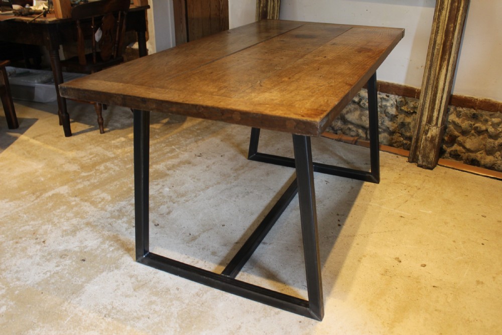 An antique George III oak plank table top with a warm brown patina mounted on a modern dark metal trapezoidal frame. View II