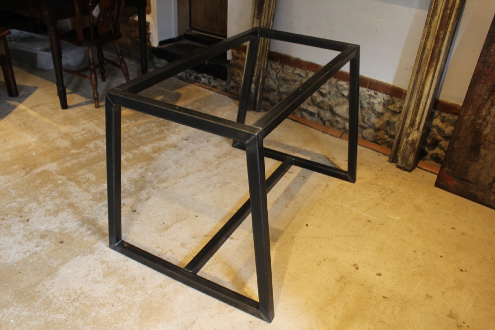 An antique George III oak plank table top with a warm brown patina mounted on a modern dark metal trapezoidal frame. View III