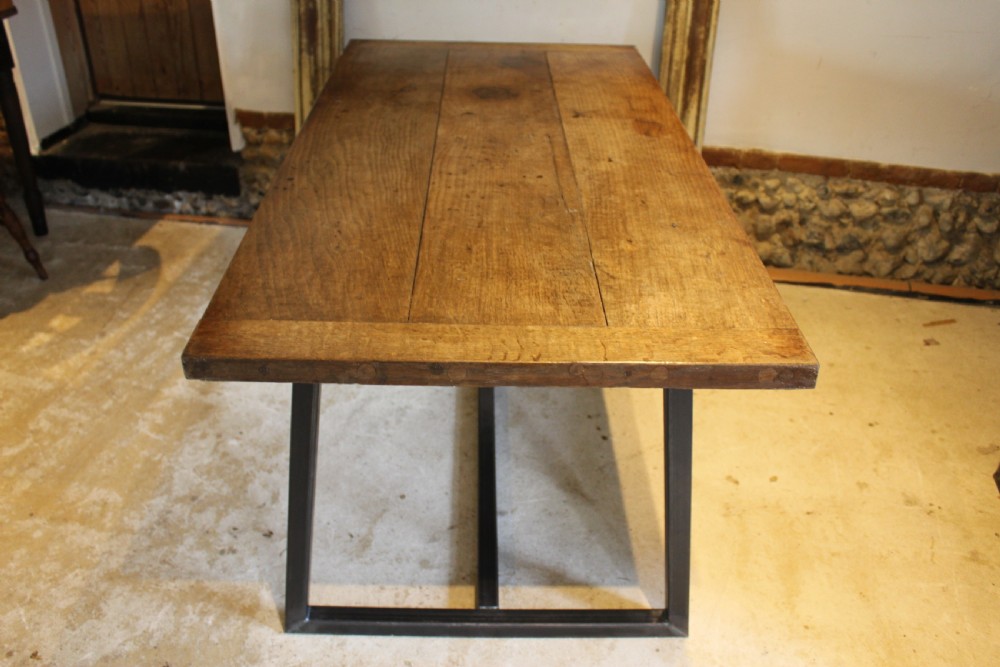 An antique George III oak plank table top with a warm brown patina mounted on a modern dark metal trapezoidal frame. View XII