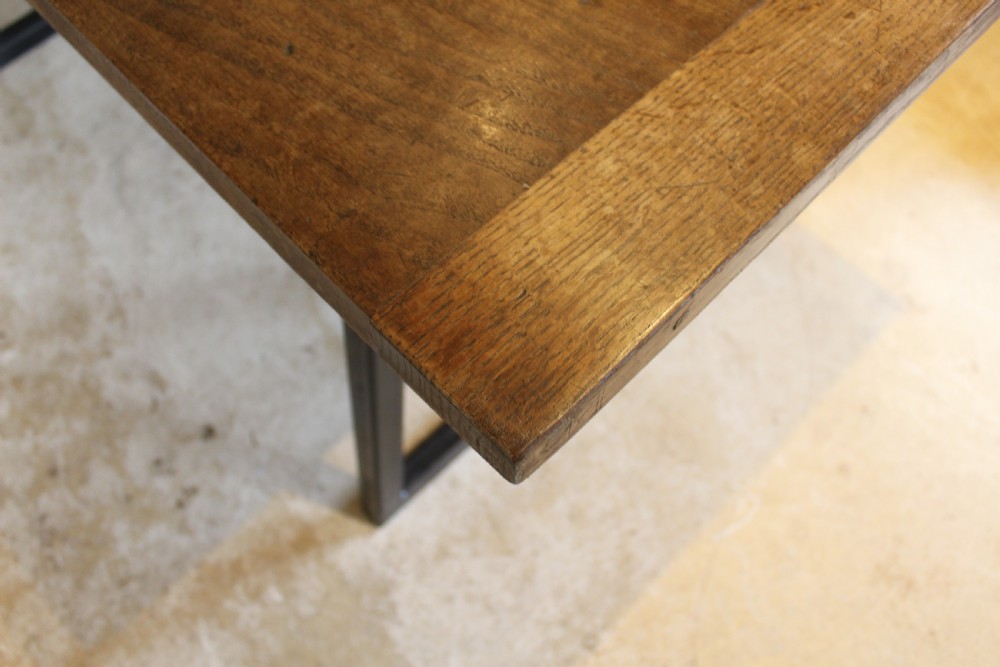 An antique George III oak plank table top with a warm brown patina mounted on a modern dark metal trapezoidal frame. View XIII