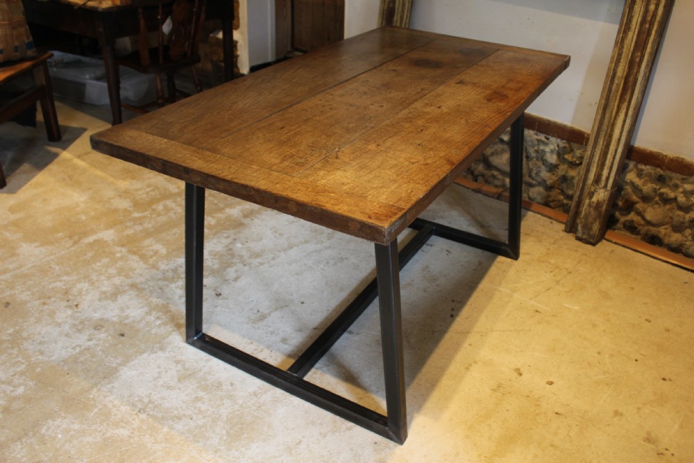 An antique George III oak plank table top with a warm brown patina mounted on a modern dark metal trapezoidal frame. View XIV