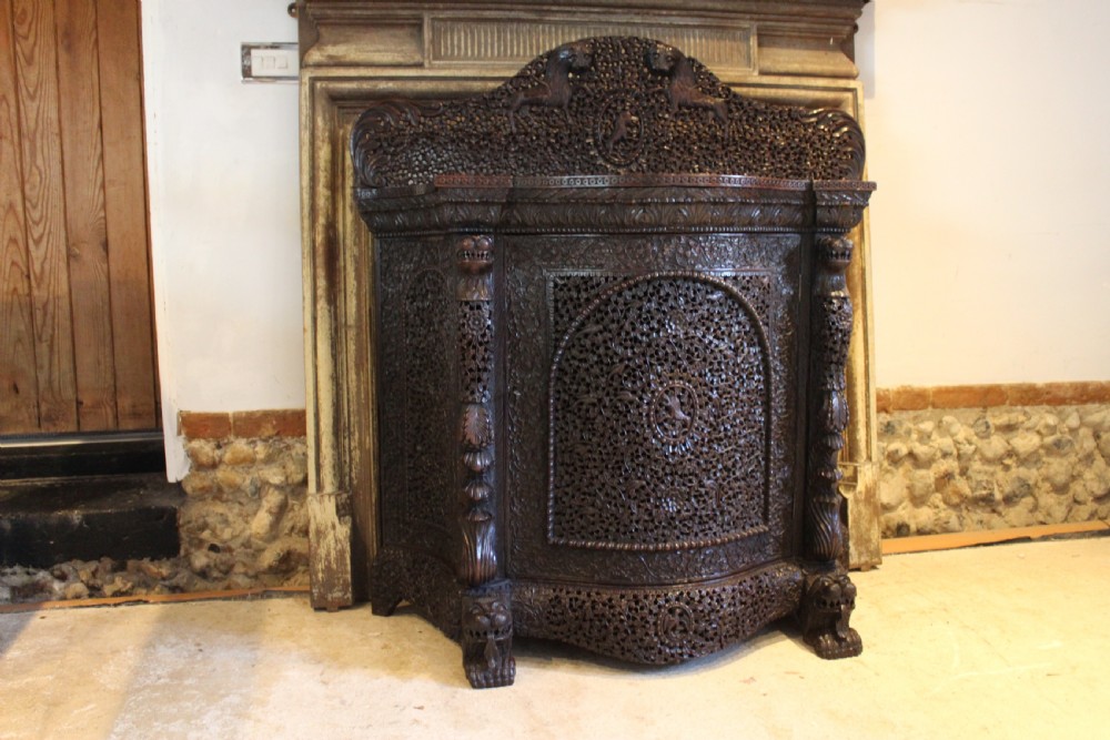 A late 19th-century dark padauk wood cabinet featuring intricate hand-carved pierced floral decoration, a carved gallery back, and lion-form supports. View II