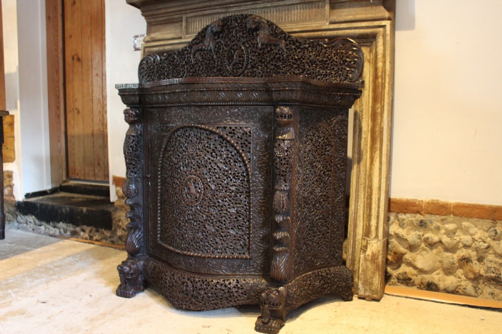 A late 19th-century dark padauk wood cabinet featuring intricate hand-carved pierced floral decoration, a carved gallery back, and lion-form supports. View III