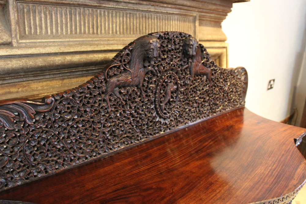 A late 19th-century dark padauk wood cabinet featuring intricate hand-carved pierced floral decoration, a carved gallery back, and lion-form supports. View V