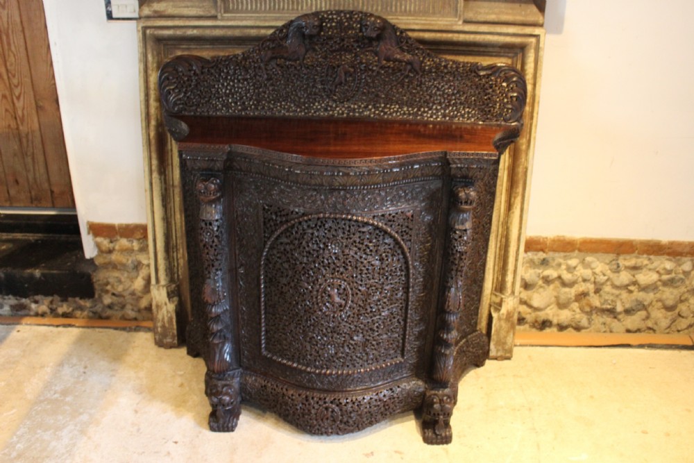 A late 19th-century dark padauk wood cabinet featuring intricate hand-carved pierced floral decoration, a carved gallery back, and lion-form supports. View VIII