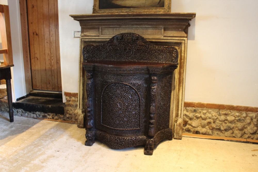 A late 19th-century dark padauk wood cabinet featuring intricate hand-carved pierced floral decoration, a carved gallery back, and lion-form supports. View XI