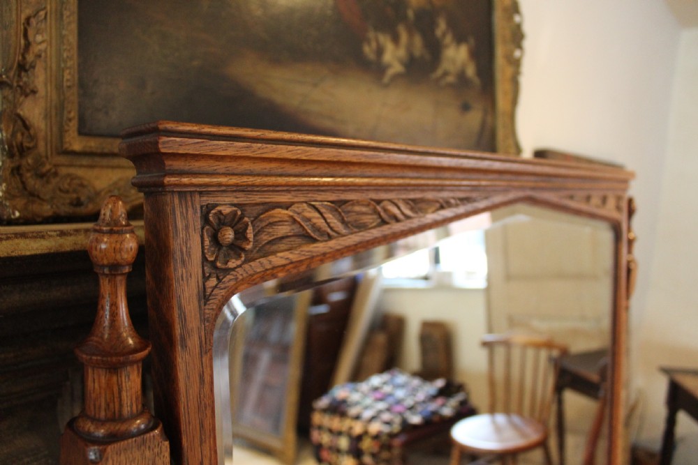 An Arts and Crafts solid oak dressing table featuring a central swinging mirror, carved spandrels, seven drawers with drop handles, and a kneehole stretcher base. View IV
