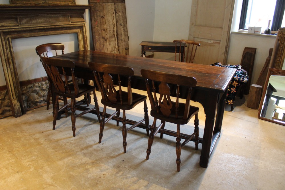 An 18th-century dark oak refectory dining table featuring a plank top, single end drawer, and square legs joined by a perimeter stretcher. View II