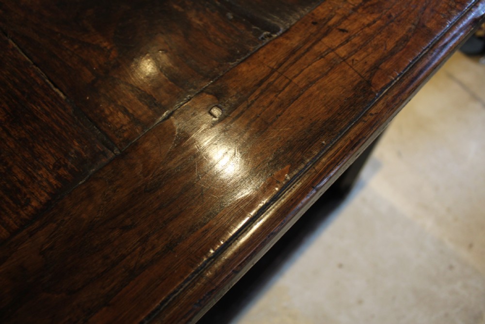 An 18th-century dark oak refectory dining table featuring a plank top, single end drawer, and square legs joined by a perimeter stretcher. View III