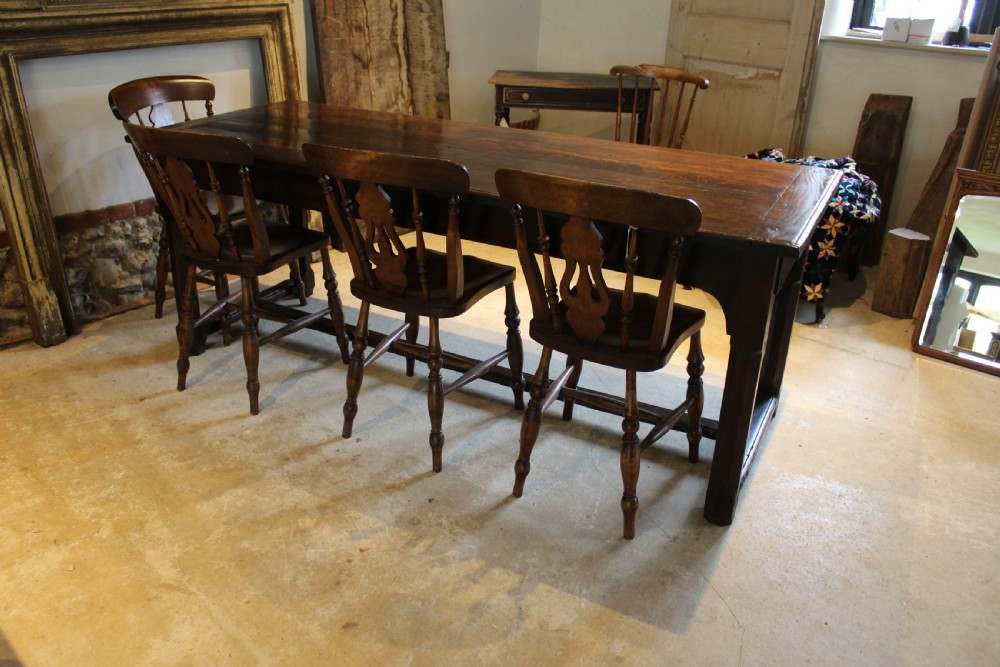 An 18th-century dark oak refectory dining table featuring a plank top, single end drawer, and square legs joined by a perimeter stretcher. View XI