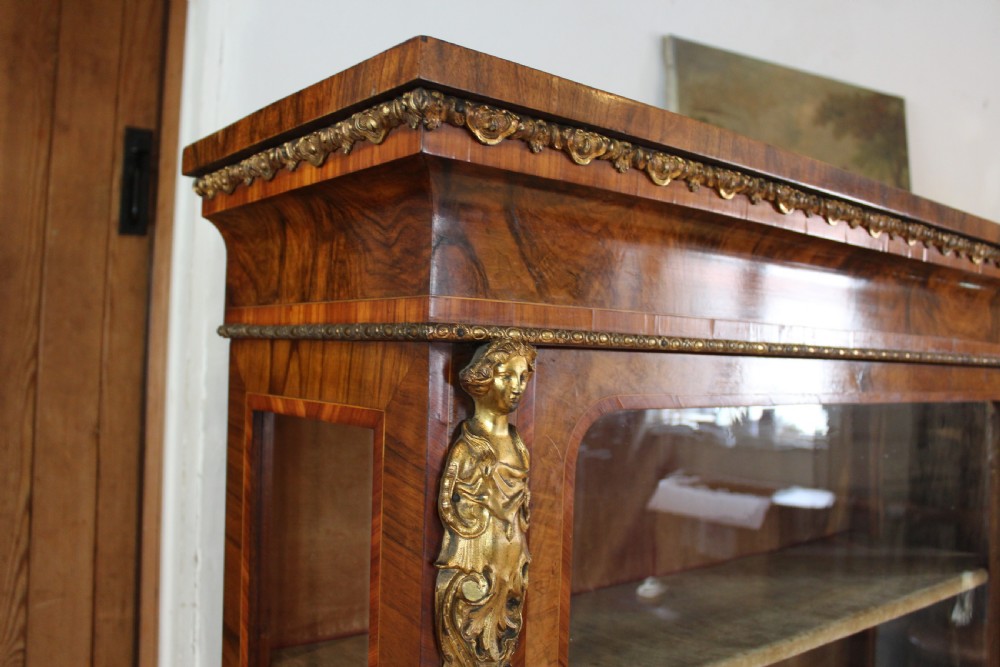 A pair of 19th-century Victorian walnut display cabinets featuring glazed single doors, adjustable interior shelves, and ornate gilt-bronze mounts on the corners and base. View IV