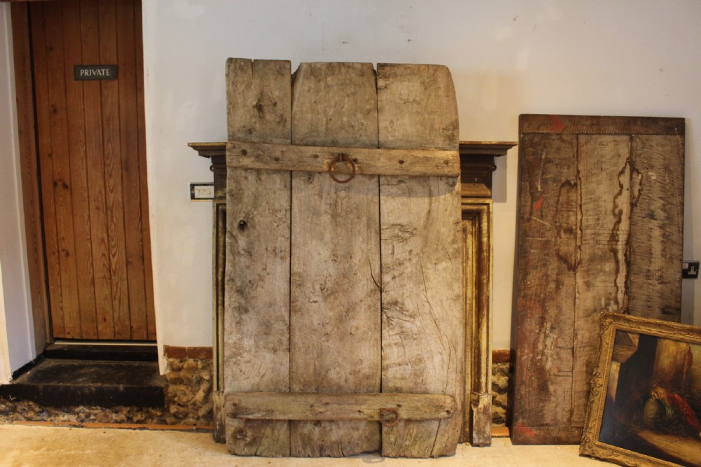 An 18th century elm wood threshing board with embedded dark flint stones leaning vertically against an interior wall. View III