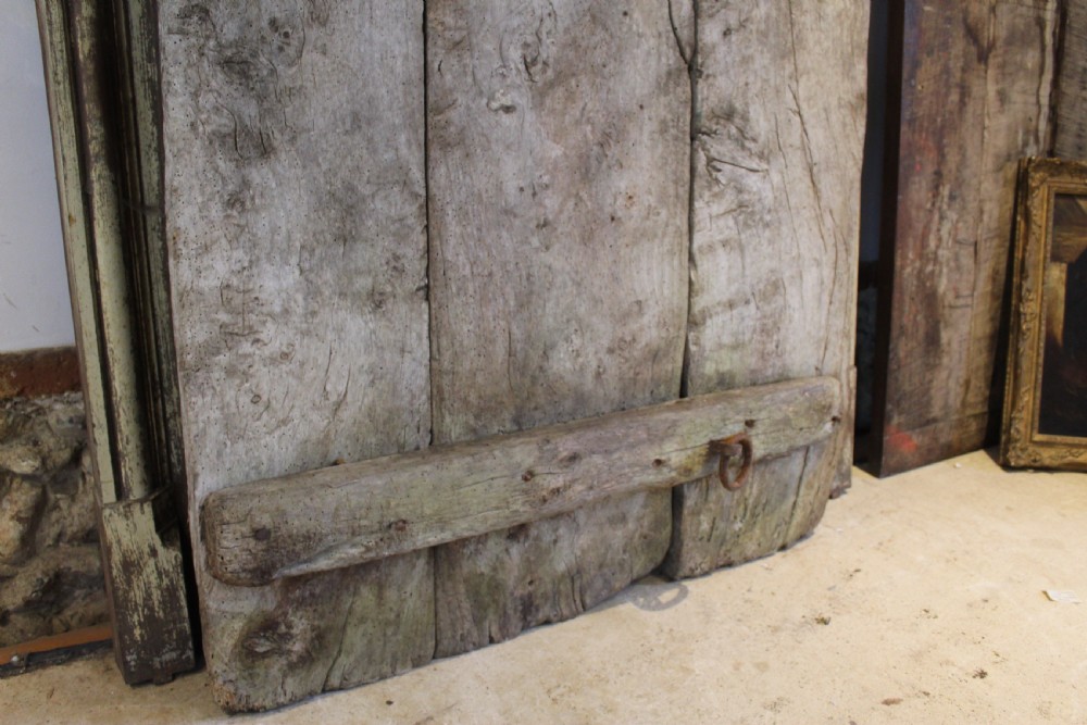 An 18th century elm wood threshing board with embedded dark flint stones leaning vertically against an interior wall. View IV
