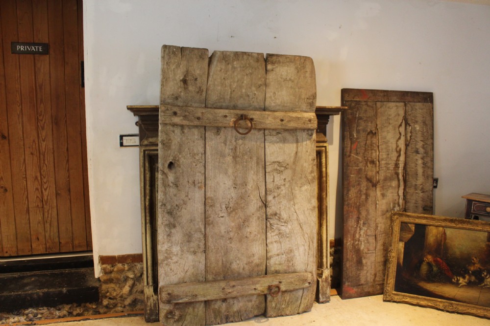 An 18th century elm wood threshing board with embedded dark flint stones leaning vertically against an interior wall. View XI