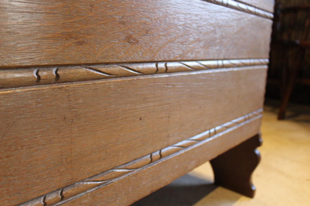 A 1930s limed oak coffer chest with carved horizontal rope twist detailing and cutout slab end feet. View II