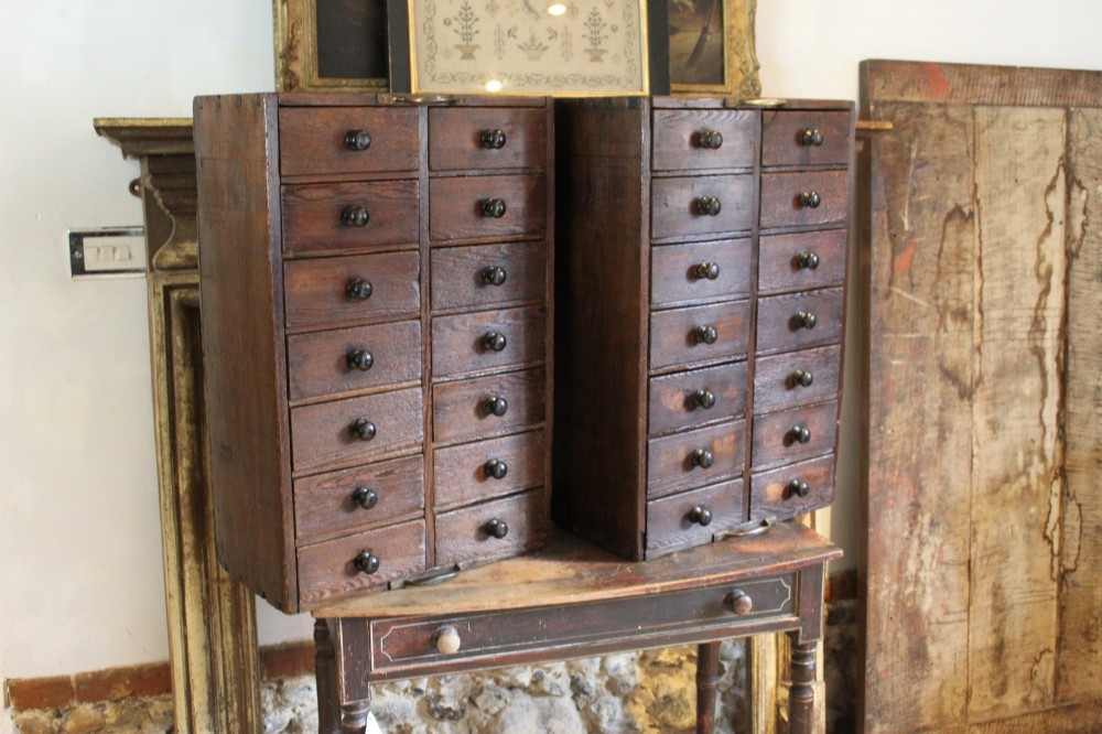 A pair of dark brown Victorian pine specimen cabinets, each featuring twin columns of eight small drawers fitted with turned wooden handles.