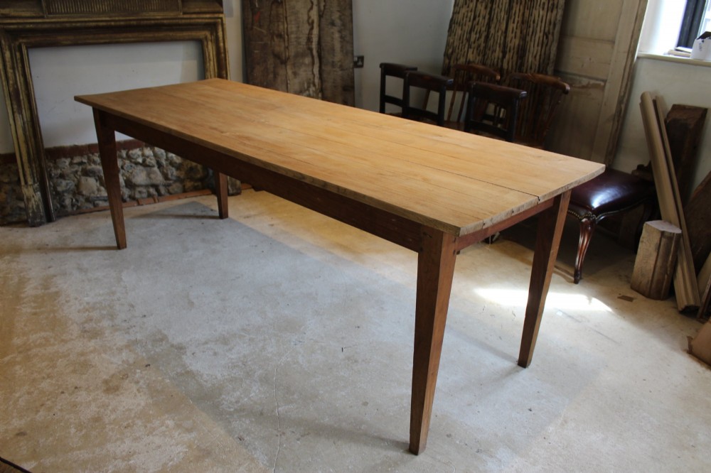 A long antique oak refectory dining table featuring a planked wood top and four square tapered legs.