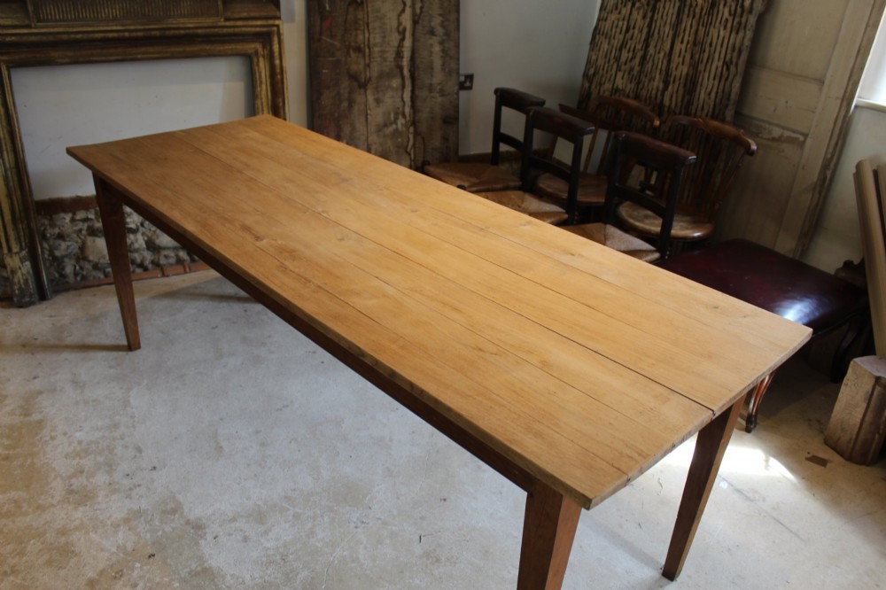 A long antique oak refectory dining table featuring a planked wood top and four square tapered legs. View III