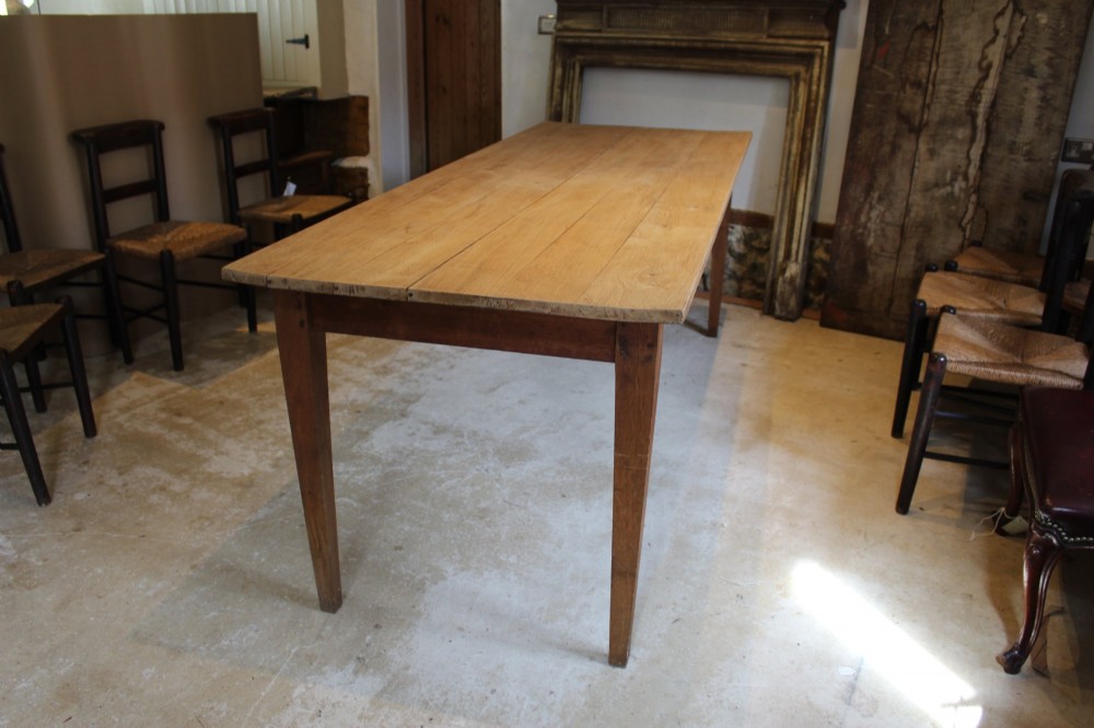 A long antique oak refectory dining table featuring a planked wood top and four square tapered legs. View IV