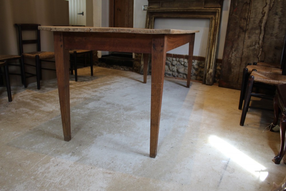 A long antique oak refectory dining table featuring a planked wood top and four square tapered legs. View VI