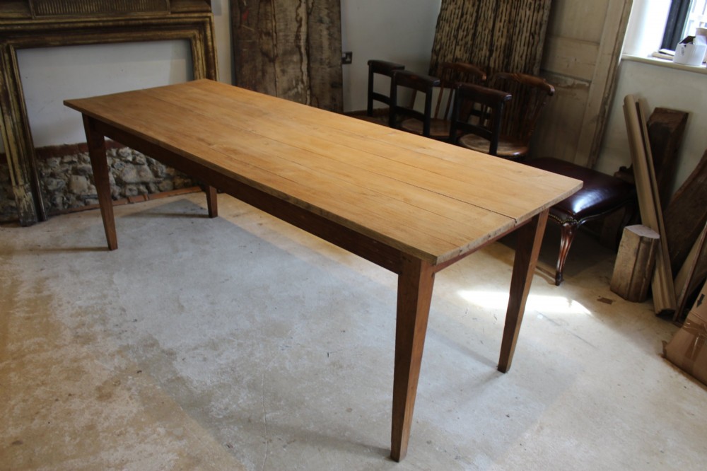 A long antique oak refectory dining table featuring a planked wood top and four square tapered legs. View IX