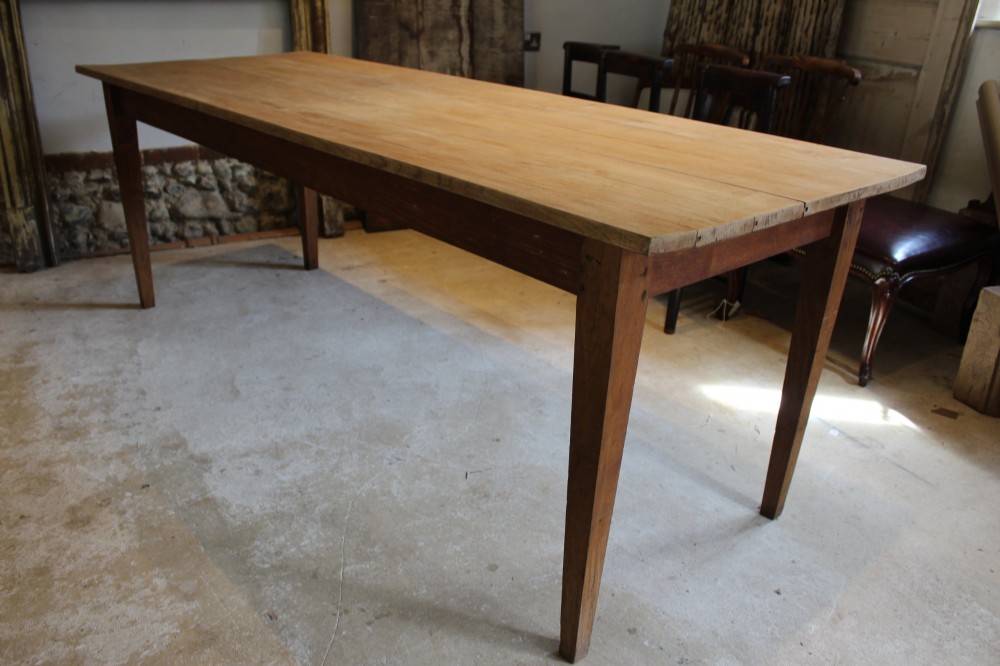 A long antique oak refectory dining table featuring a planked wood top and four square tapered legs. View X