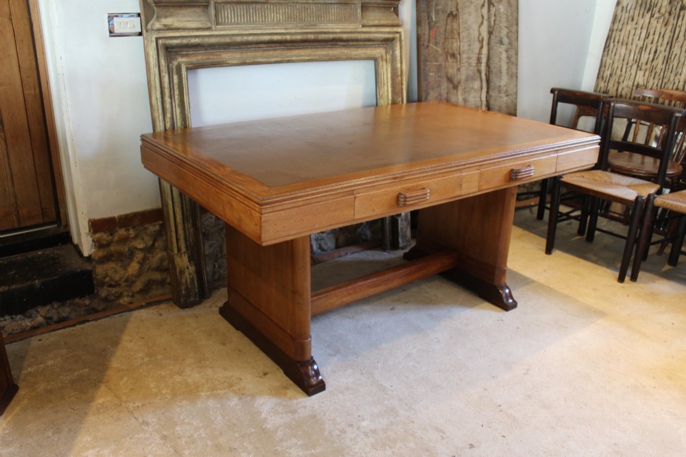 An Art Deco walnut desk featuring a rectangular top with an inset writing surface, frieze drawers with ribbed handles, and a trestle-style base with a low stretcher.